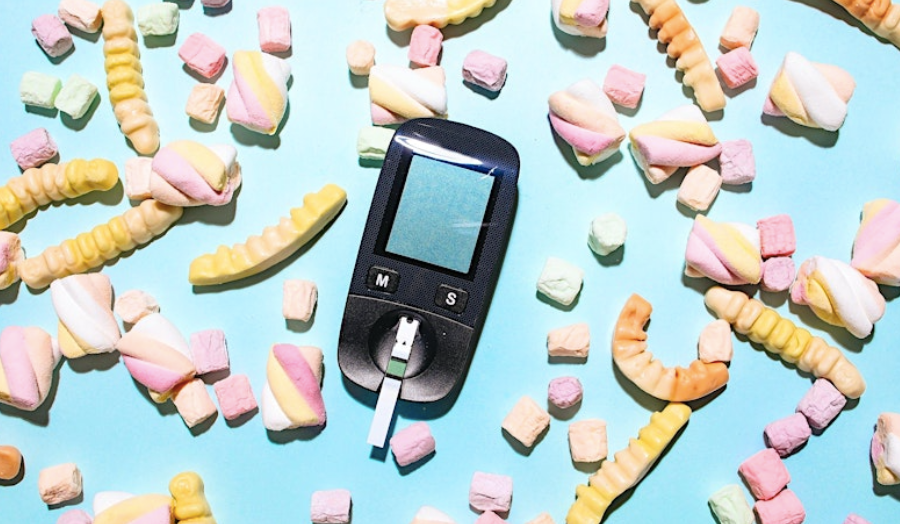 An image of a blood glucose meter surrounded by marshmallows. 
